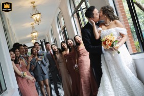 Whimsical wedding moment captured as couple shares a kiss at Shanghai's Ruijin Hotel A romantic scene at Ruijin Hotel in Shanghai, China, as the bride and groom share a kiss surrounded by their beloved friends. The camera angle adds a whimsical touch, capturing the kiss in a unique frame.